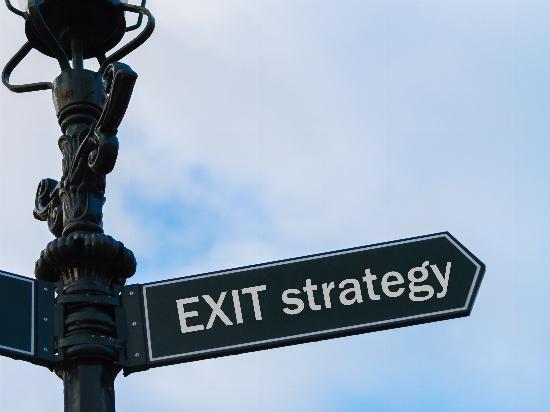 A streetlight with a directional arrow reading, "Exit Strategy."