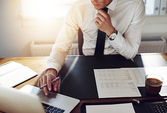 A man at a computer researching and taking notes on angel investing.